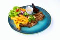 Steak pork chop topped with black pepper sauce and sausage with french fries and vegetable salad on dish with white background. Royalty Free Stock Photo