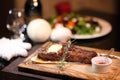 Rib eye steak on the New Year`s table. Steak rib eye roast on a wooden board with sauce and salt. Beef steak on wooden plate