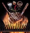 Steak cooking. Conceptual picture. Steak with spices and cutlery under burning grill grate Royalty Free Stock Photo