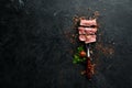 Steak Ribeye grill on fork on black stone background. Top view.