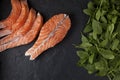 Steak and slices of salmon filet and a bunch of spinach leaves on a black textured background. Keto Diet Ingredients