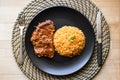 Steak with tomato sauce and bulgur rice in a black plate. Royalty Free Stock Photo