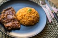 Steak with tomato sauce and bulgur rice in a black plate. Royalty Free Stock Photo