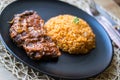 Steak with tomato sauce and bulgur rice in a black plate. Royalty Free Stock Photo