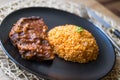 Steak with tomato sauce and bulgur rice in a black plate. Royalty Free Stock Photo