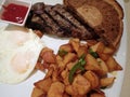 Steak with two eggs over easy, two slices of rye bread, potatos Royalty Free Stock Photo