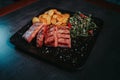 Steaks baked potato and a greeny leaf salad  on a black plate Royalty Free Stock Photo