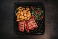 Steaks baked potato and a greeny leaf salad  on a black plate Royalty Free Stock Photo