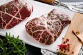 Steaks Raw. Raw cowboy steak, marbled beef meat with spices rosemary and pepper on white marble slate and grey table background. T Royalty Free Stock Photo