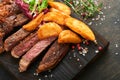 Steaks. Sliced grilled meat steak New York, Ribeye or Chuck roll with with garnished with salad and french fries on black marble Royalty Free Stock Photo