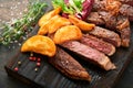 Steaks. Sliced grilled meat steak New York, Ribeye or Chuck roll with with garnished with salad and french fries on black marble Royalty Free Stock Photo