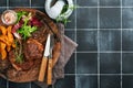 Steaks. Sliced grilled meat steak New York, Ribeye or Chuck roll with garnished with salad and french fries on black marble board Royalty Free Stock Photo