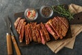 Steaks. Sliced grilled meat steak New York or Ribeye with spices rosemary and pepper on black marble board on old wooden backgroun Royalty Free Stock Photo