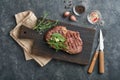 Steaks. Sliced grilled meat steak New York or Ribeye with spices rosemary and pepper on black marble board on old wooden Royalty Free Stock Photo