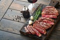 Steaks. Sliced grilled meat steak New York or Ribeye with spices rosemary and pepper on black marble board on old wooden Royalty Free Stock Photo