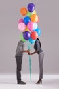 Stealing a kiss behind the balloons. Studio shot of a couple hiding behind a bunch of balloons.