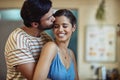 Stealing a quick kiss. an affectionate young couple kissing in their kitchen at home.