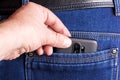 Stealing a smartphone from a pocket in the back. The burglar pulls the phone out of the back pocket of his denim pants Royalty Free Stock Photo