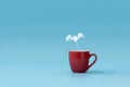 Steam in bat shape flying from coffee cup against blue background. Morning drink. Halloween celebration concept. Copy space