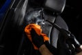 Steam cleaning of leather seat after foam washing. Worker in auto cleaning service clean car inside. Car interior