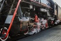 Steam comes under the wheels of the old locomative when departing from the station. Black iron train with red details Royalty Free Stock Photo