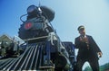 A steam engine conductor checks the time as he stands near the cowcatcher on the front, Eureka Springs, Arkansas