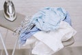 Steam iron on ironing board next to pile of cotton shirts Royalty Free Stock Photo