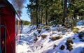 Steam locomotive drives through the trees with a blue sky. Winter in the snow covered mountains. Dynamics through motion blur Royalty Free Stock Photo