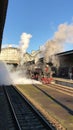 Steam locomotive emits a loud signal with clouds of steam and smoke, departure from the station