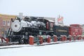 A steam locomotive sits in the snow covered small town Royalty Free Stock Photo