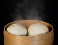 Steam rising from cooked buns in bamboo steamer basket