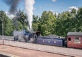 A steam train, bellowing steam and smoke at the aviemore train station