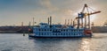 Steamboat carrying tourists around the Hamburg harbor. An excursion ship in Hamburg against the sun. Traditional paddle steamer on