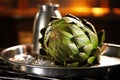 steamed artichoke on metal dish, steam visible