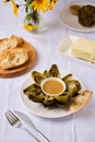 Steamed artichoke with vinaigrette sauce based on oil and mustard on a white plate on a light background. Served with fresh Royalty Free Stock Photo