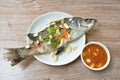 Steamed bass fish with garlic dipping spicy sauce on table