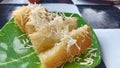 steamed cassava with cheese topping on a green plate with a black and white square base for breaking the fast