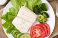 Steamed cod fish. Paleo, keto, fodmap healthy diet with vegetables on white plate on wooden table, top view.