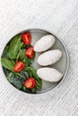 Steamed cutlets of three kinds of white meat with fresh spinach and tomatoes. Top view