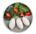 Steamed cutlets of three kinds of white meat with fresh spinach and tomatoes. Top view