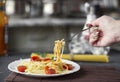 Steamed pasta spaghetti on a fork in tomato sauce with cheese and parsley, female hand. Italian spaghetti pasta on a dark stone Royalty Free Stock Photo