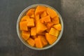 Steamed pumpkin in a glass bucket on dark background. Healthy carbohydrates