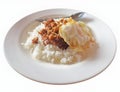 Steamed rice topped with fried chicken with garlic and pepper and fried egg. Arranged on a white plate and spoon. isolated white