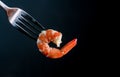 Steamed shrimp on fork isolated on dark background with copy space. Seafood buffet in restaurant concept. Use for seafood buffet