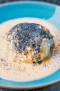 Steamed sweet dumpling bun topped with poppy seeds and vanilla sauce.