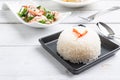 Steamed Thai jasmine rice in black plate with paco fern spicy sa