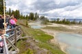 Steaming aqua hot spring, with people on boardwalk, Yellowstone.