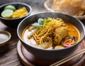 A steaming bowl of khao soi, a northern Thai curry noodle soup with tender chicken and crispy fried noodles on top