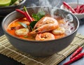 A steaming bowl of Tom Yum Goong, brimming with plump shrimp, aromatic lemongrass, and fiery chili peppers