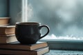 Steaming coffee cup resting on a stack of books near a window with a winter view outside Royalty Free Stock Photo